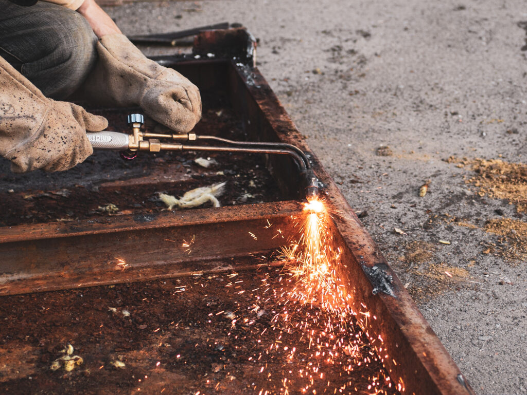 Welder-Cutting-Metal-with-Torch-in-Urban-Setting